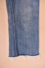 Load image into Gallery viewer, Vintage light wash blue denim jeans by Levis are shown in close up. These jeans have a raw cutoff hem.
