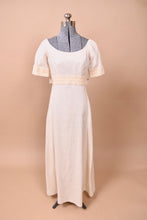 Load image into Gallery viewer, The dress faces forward on a mannequin. The piece has a lace tie at the waist and lace cuffs.
