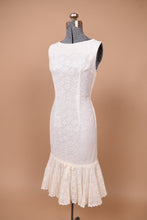 Load image into Gallery viewer, Vintage 60s white lace mermaid dress is shown from the side. This dress is sleeveless and has flattering darts on the bodice.

