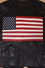 Load image into Gallery viewer, Vintage patchwork black leather vest is shown in close up. This vest has a leather red, white, and blue American flag on the back. 
