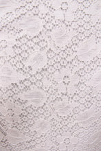 Load image into Gallery viewer, Vintage sixties white lace dress is shown in close up. This dress has a floral lace with daisy and tulip patterns.

