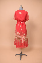Load image into Gallery viewer, Vintage nineties red flower print dress is shown from the back. This dress cinches with a bow at the waist.
