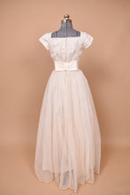 Load image into Gallery viewer, Vintage fifties princess wedding dress is shown from the back. This dress has a satin bow detail at the back of the bodice.
