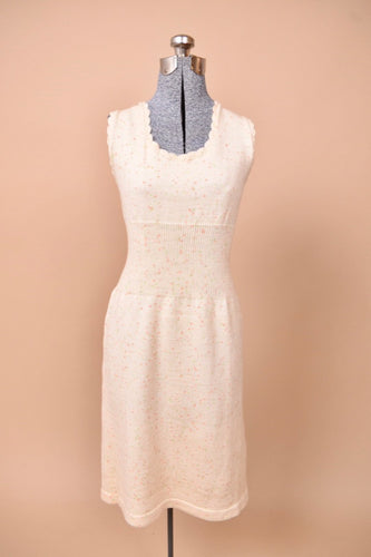 The dress is sleeveless with scalloped detailing.