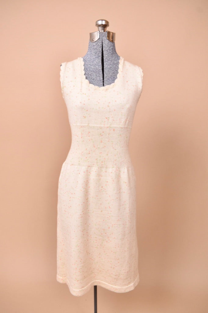 The dress is sleeveless with scalloped detailing.